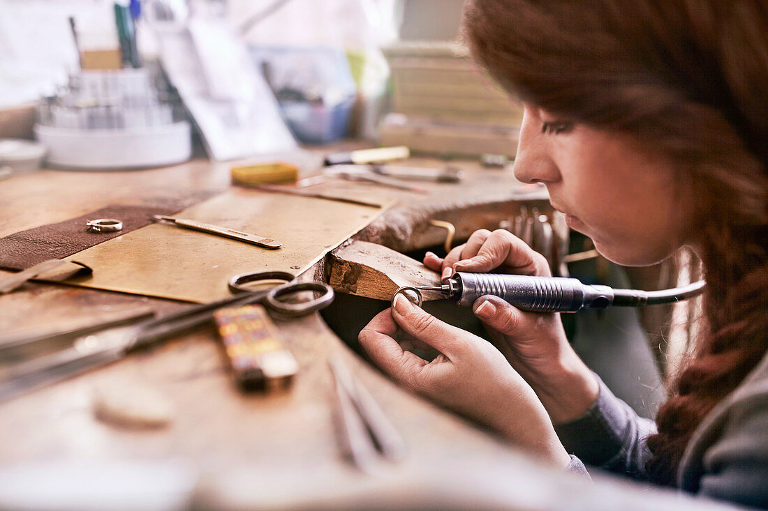 Female jeweller using equipment in workshop