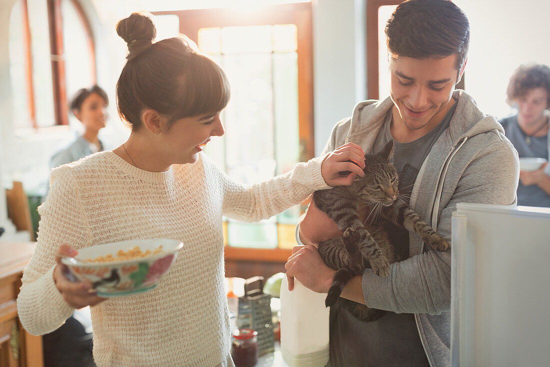 Young couple petting cat in kitchen