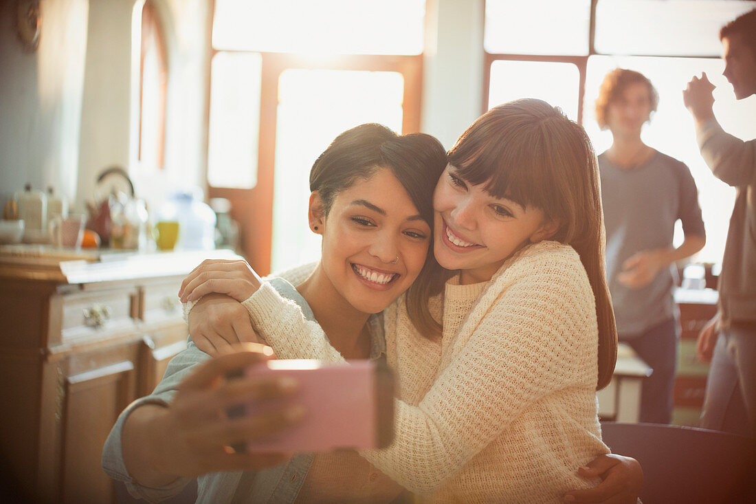 Young women friends taking selfie in apartment