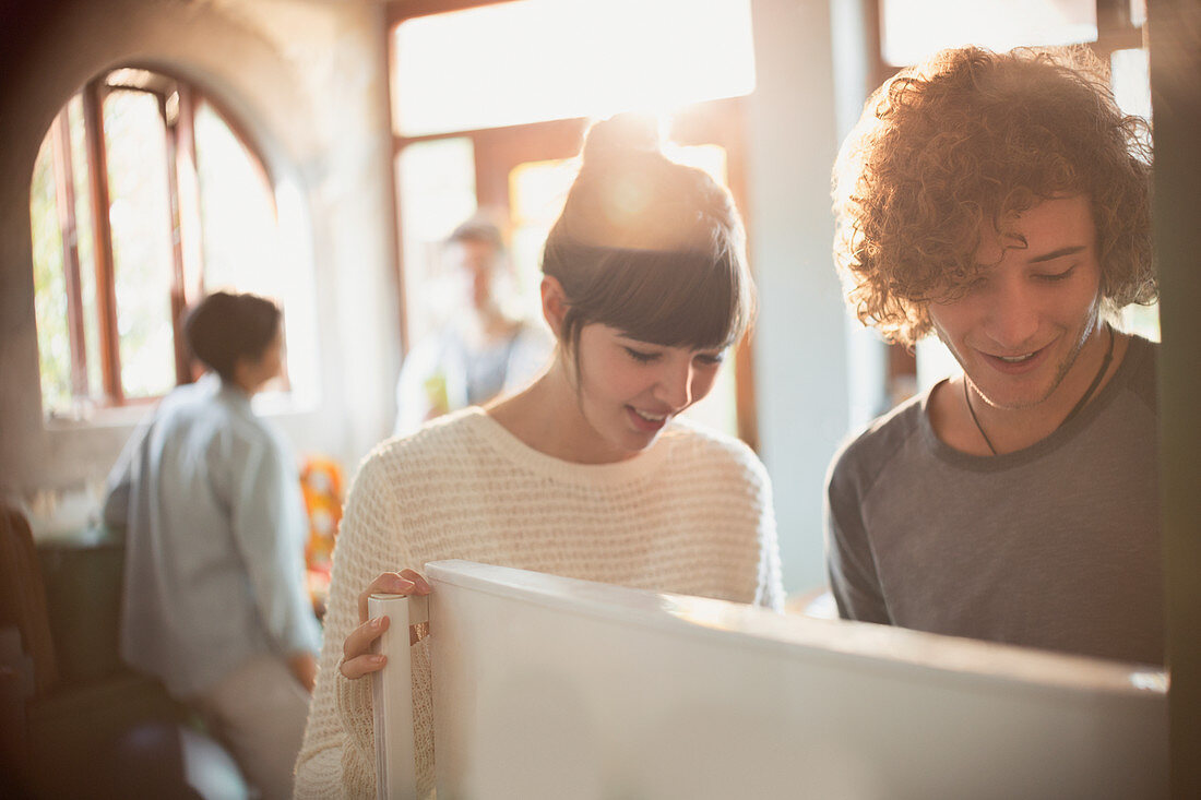 Young couple opening refrigerator in kitchen