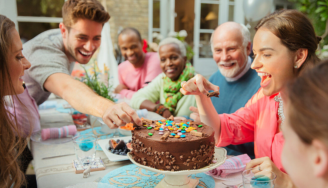 Family reaching for candy on birthday cake