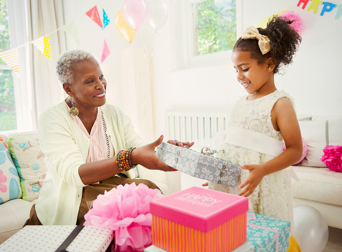 Girl giving birthday gift to grandmother at party