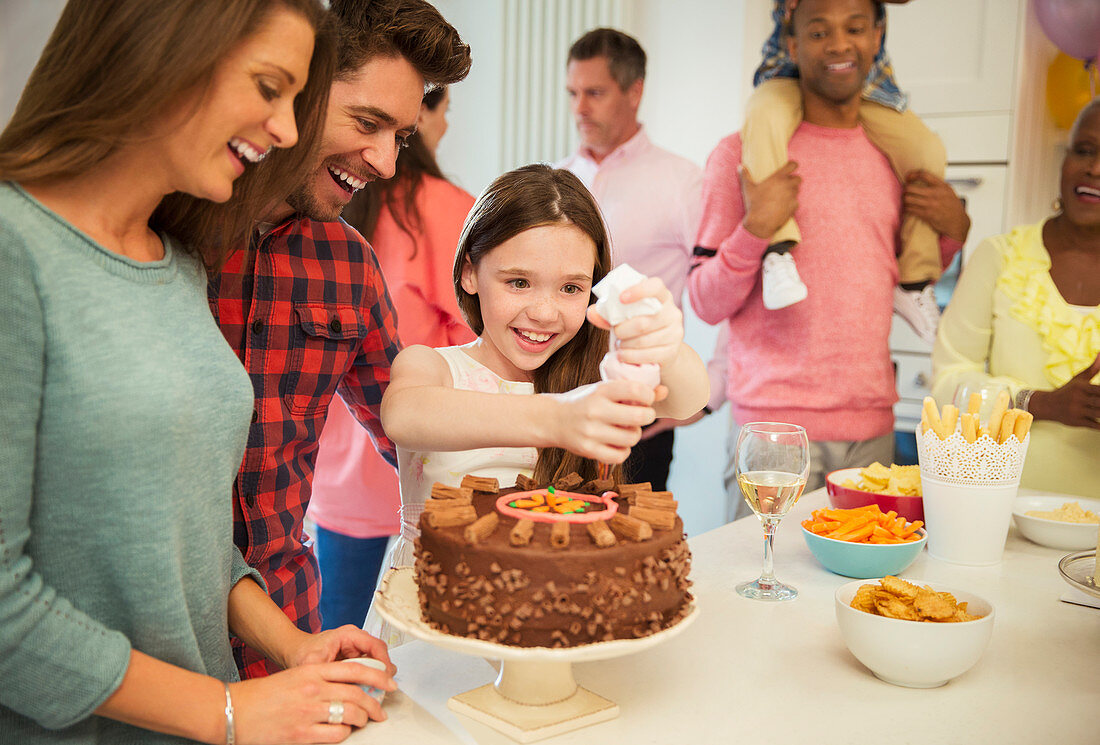 Smiling family icing chocolate cake in kitchen