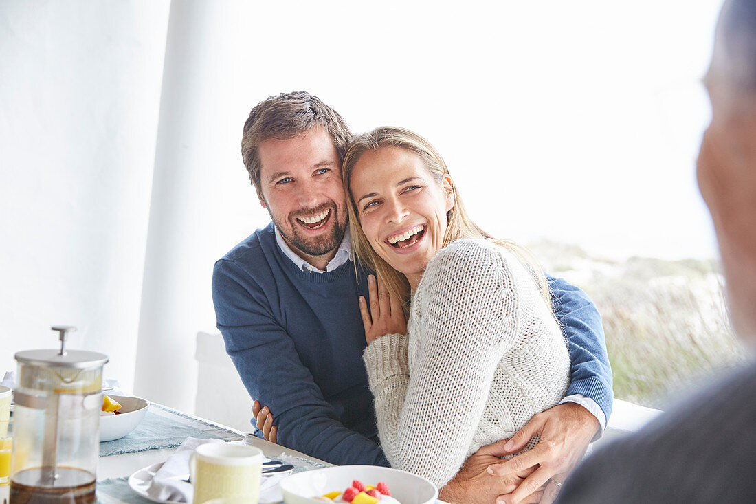 Couple laughing and hugging at patio breakfast