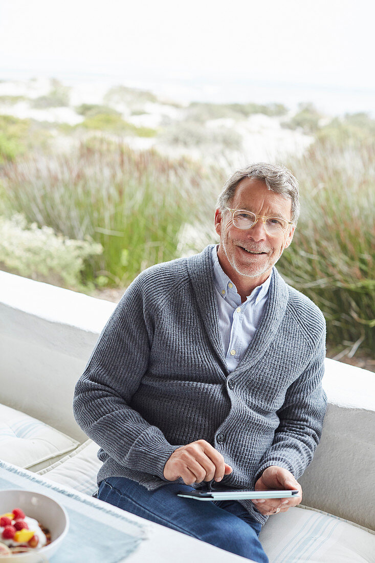 Senior man using digital tablet on beach patio