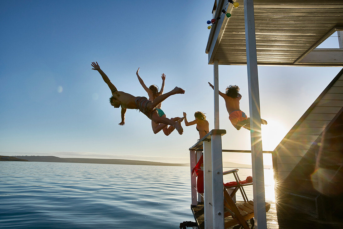 Friends jumping from summer houseboat