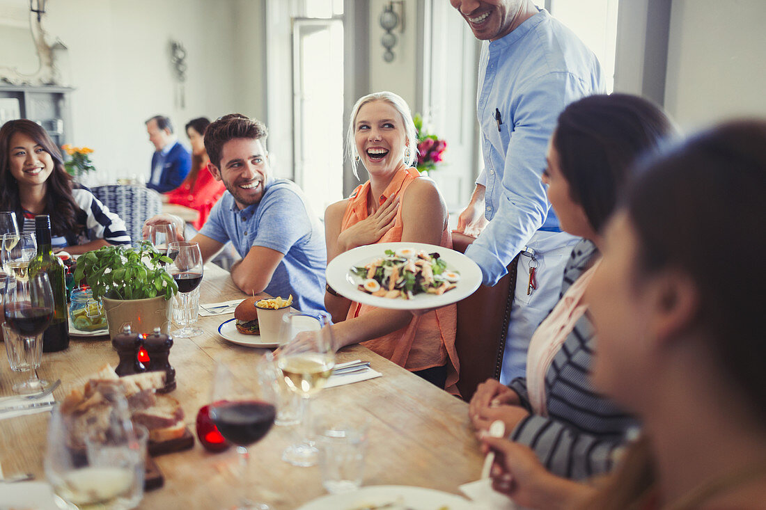 Waiter serving salad to woman dining with friends