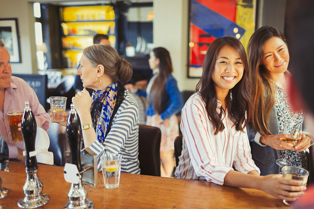 Women smiling at bartender and drinking at bar