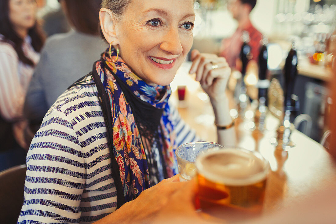Senior woman drinking beer at bar