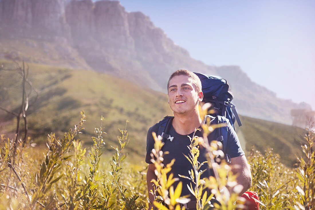 Young man with backpack hiking in valley