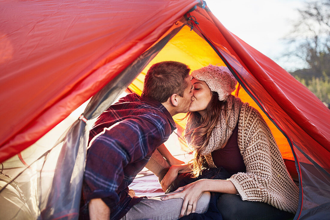 Young couple camping, kissing inside tent