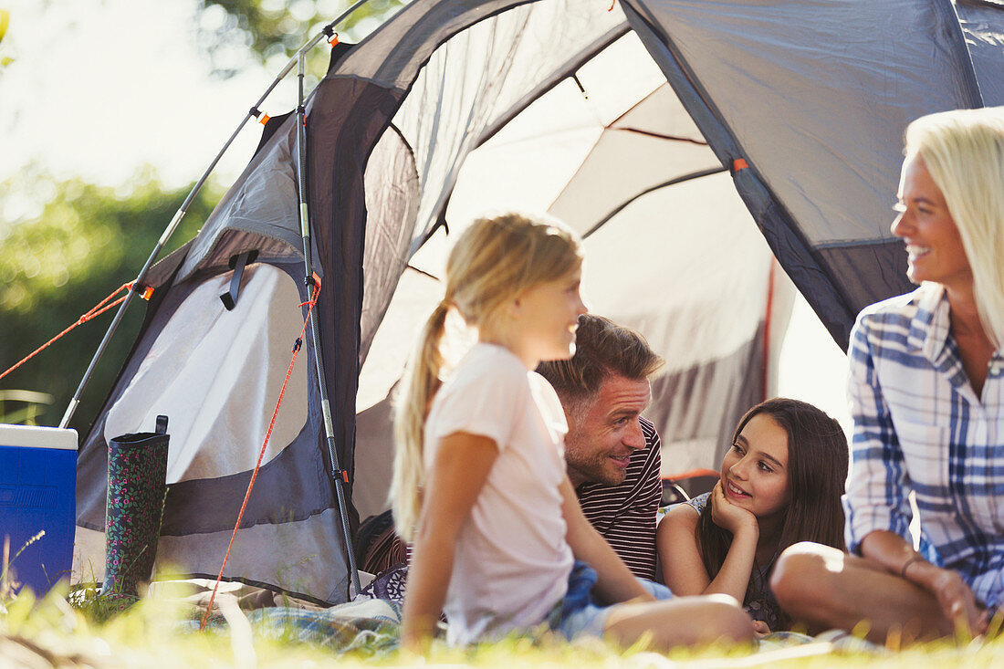 Smiling family talking and relaxing outside tent