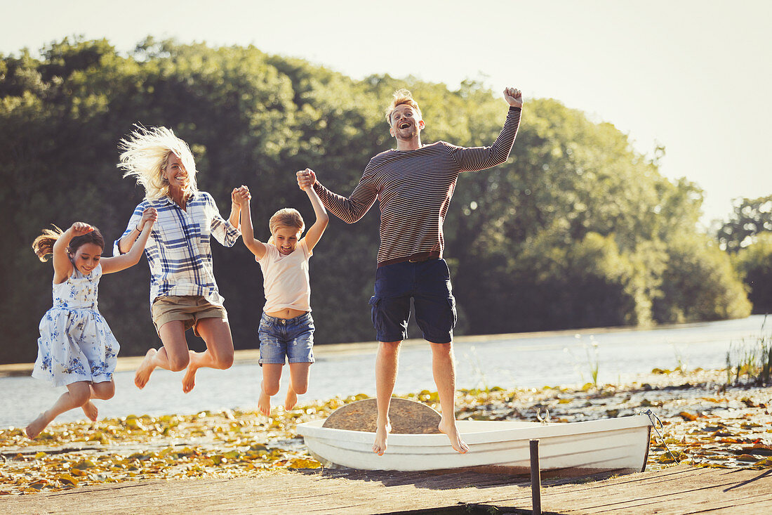 Exuberant family jumping on lake dock