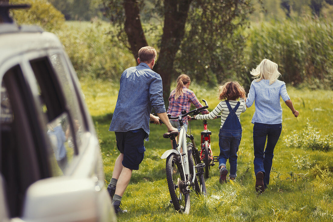 Family walking mountain bikes away from car