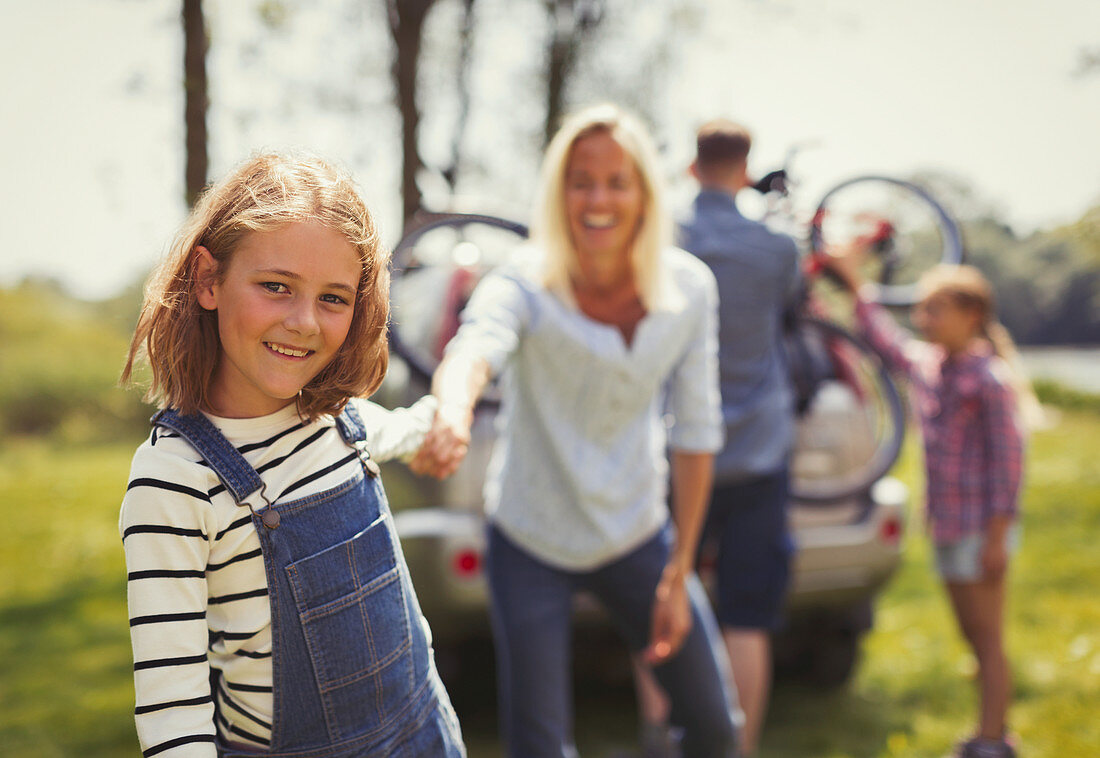 Mother and daughter with hands outside car