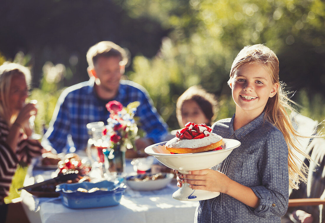 Portrait girl serving strawberry cake to family