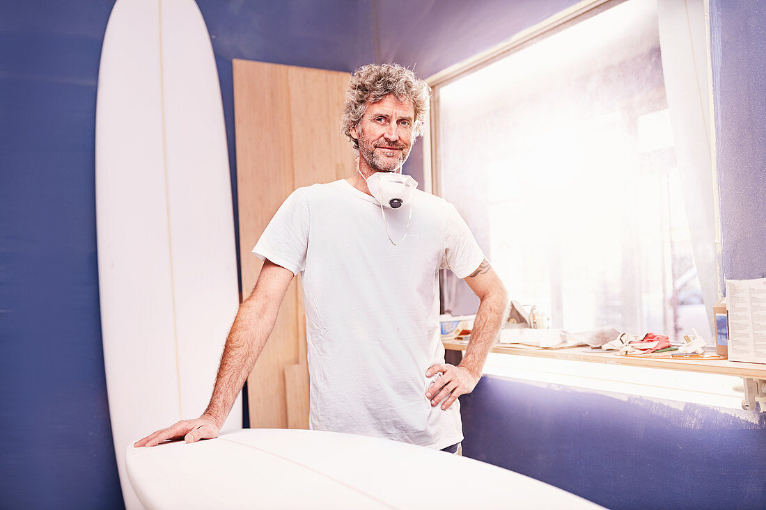 Portrait male surfboard designer sanding surfboard