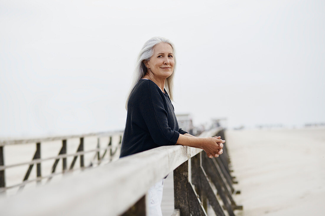 Portrait senior woman leaning on beach railing