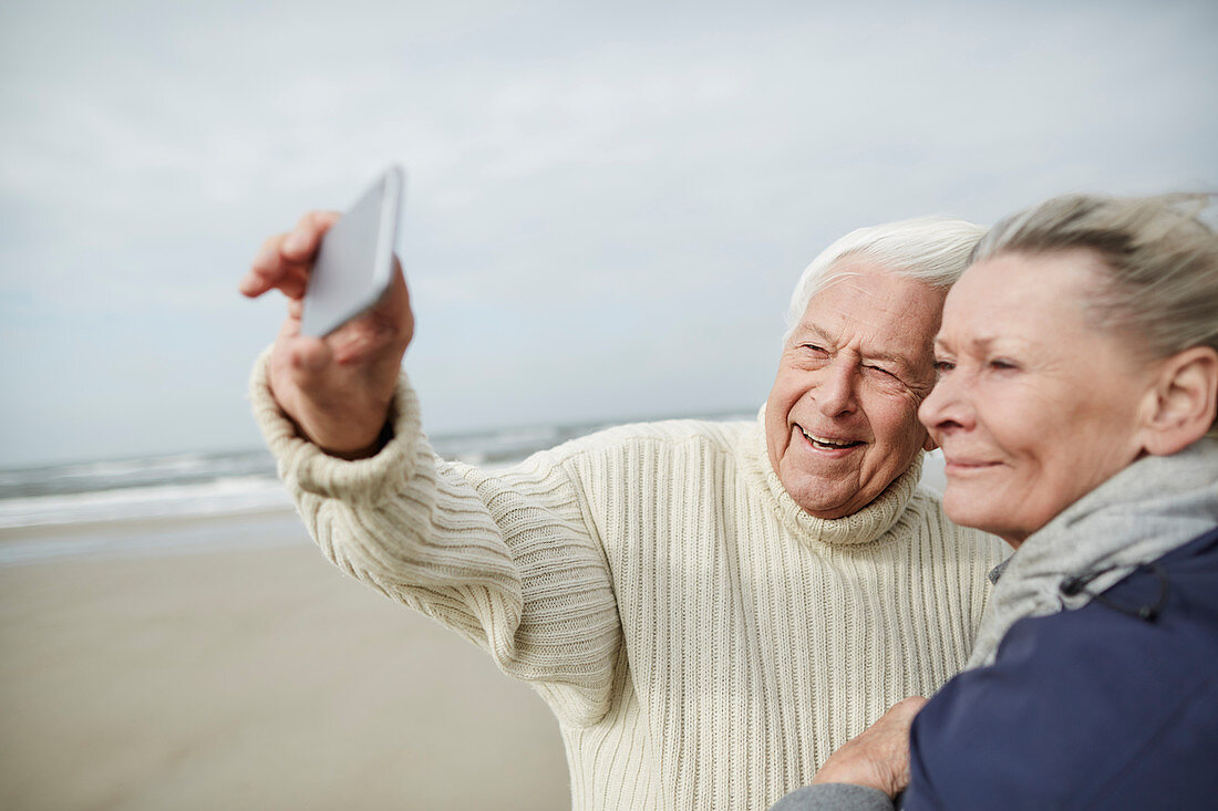 Senior couple taking selfie on beach