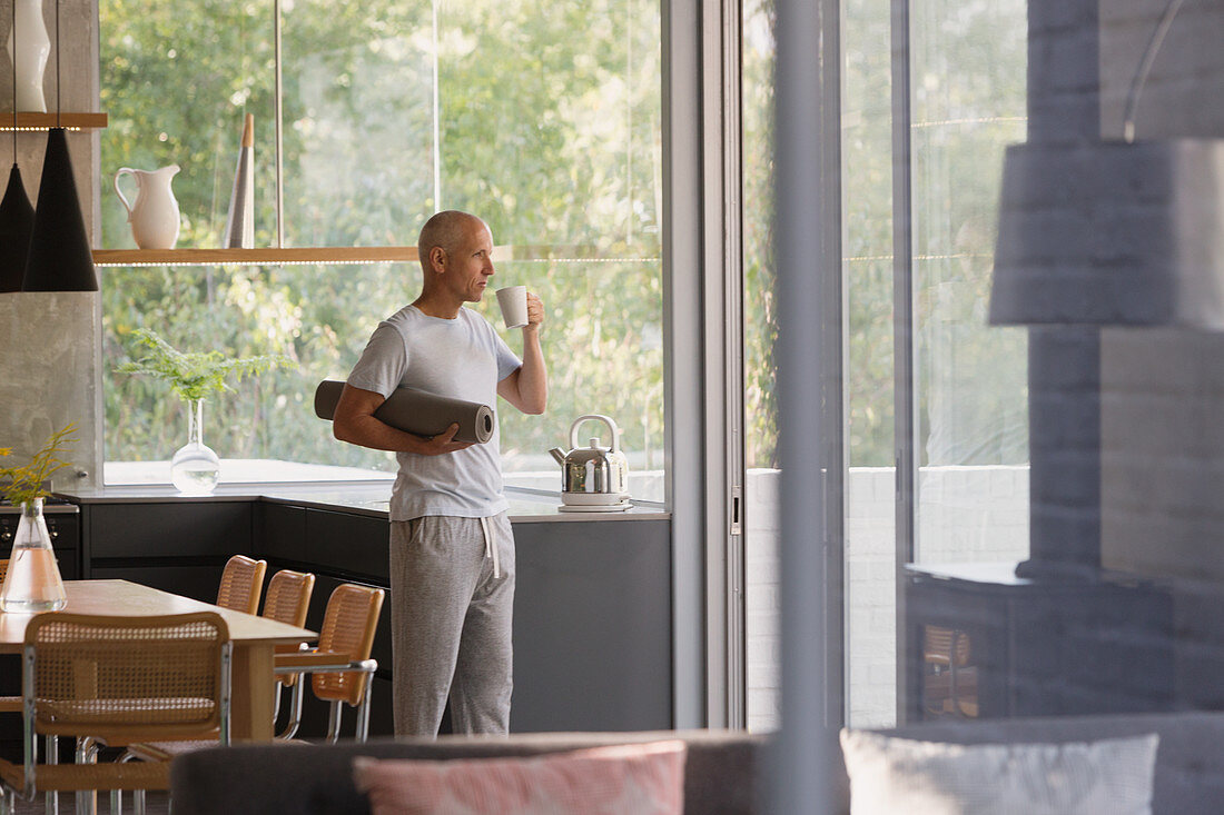 Mature man with yoga mat drinking coffee