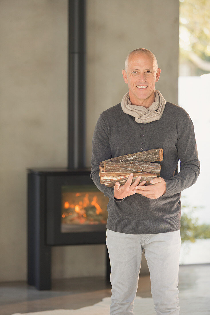 Portrait mature man holding firewood
