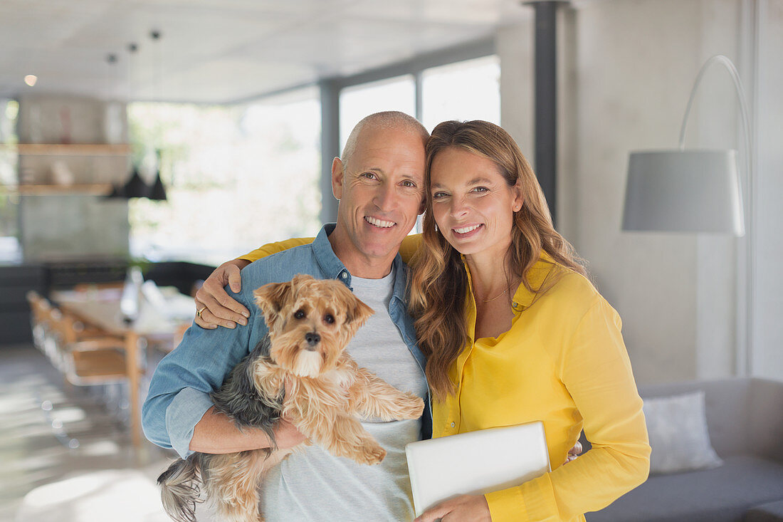 Portrait smiling mature couple hugging with dog