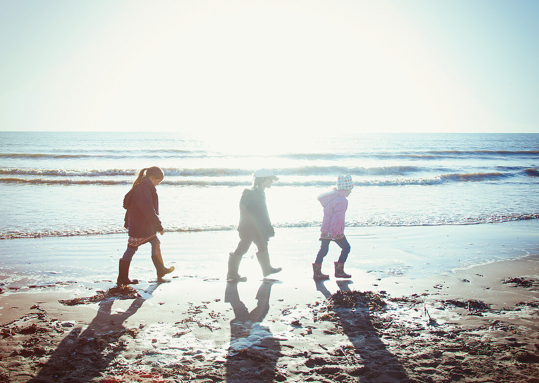 Brother and sisters walking in wet sand