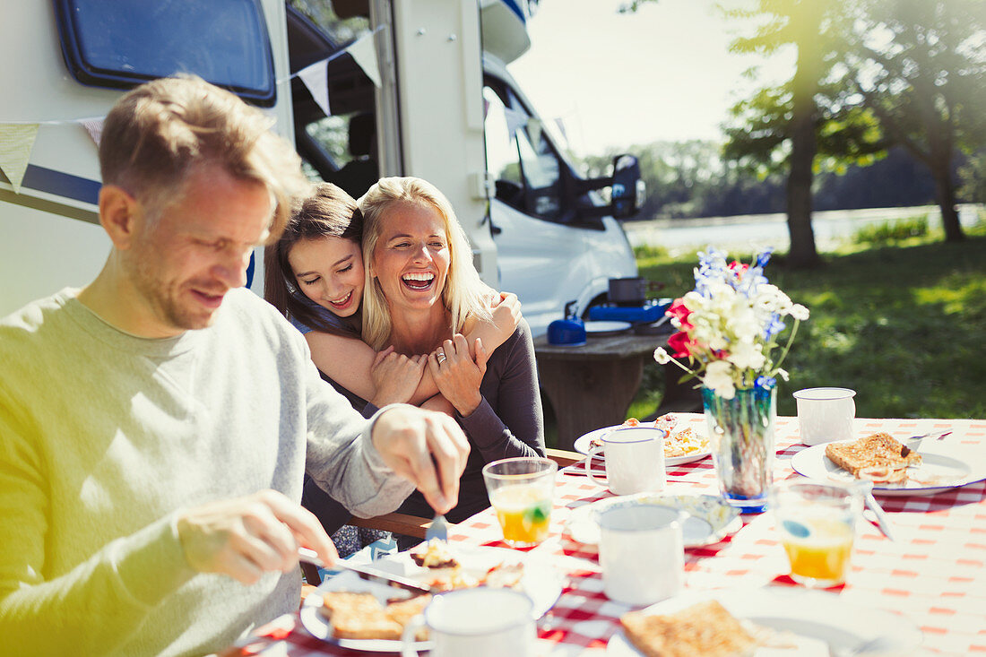 Happy family hugging and eating breakfast