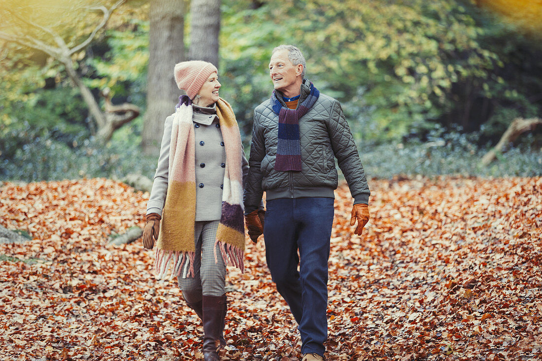 Senior couple walking in autumn leaves in park