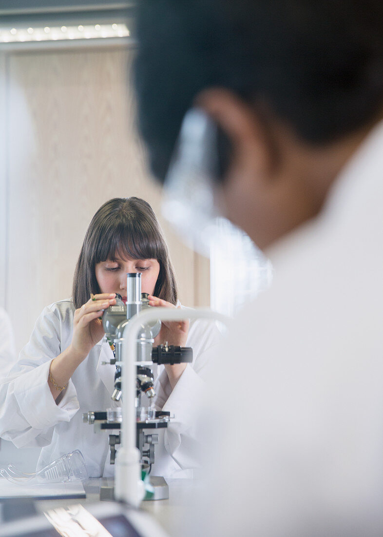 Female college student using microscope