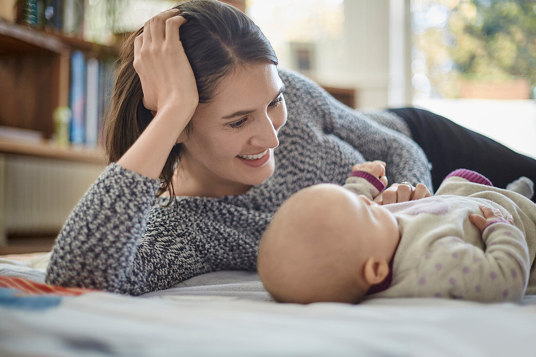 Smiling mother looking at baby daughter