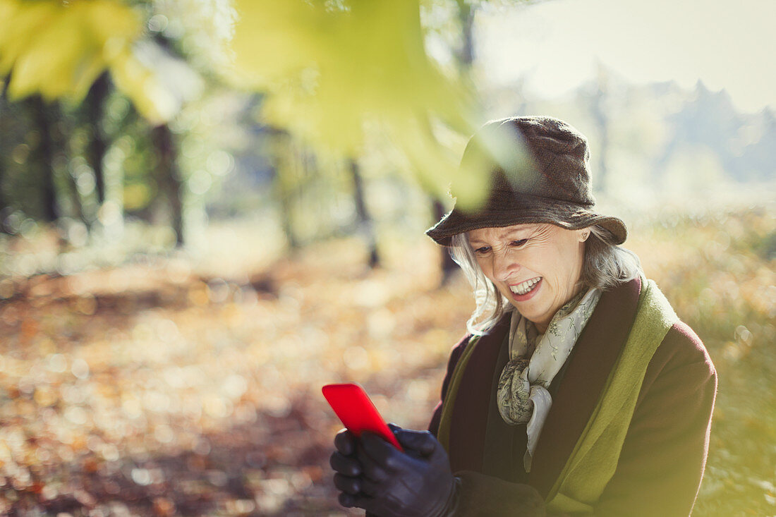 Senior woman using cell phone in autumn park