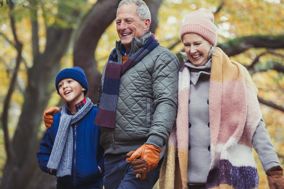 Grandparents walking with grandson in autumn park