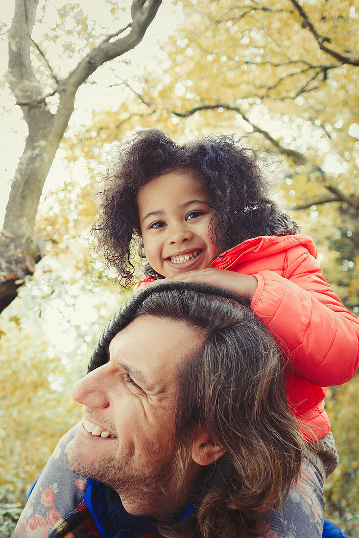 Portrait father carrying daughter on shoulders