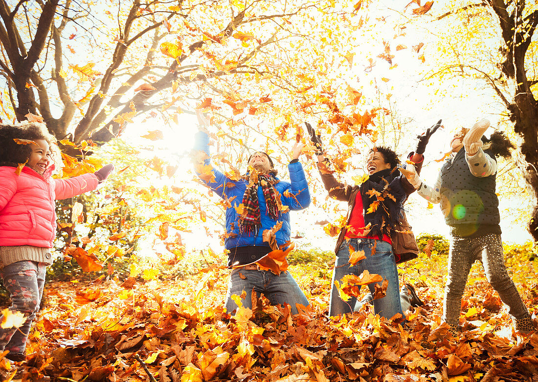 Playful young family throwing leaves in park