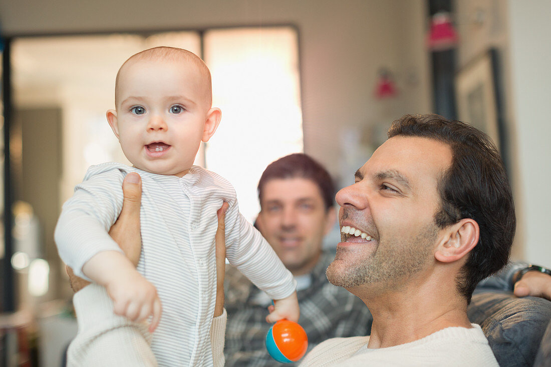 Portrait happy male gay parents holding baby son