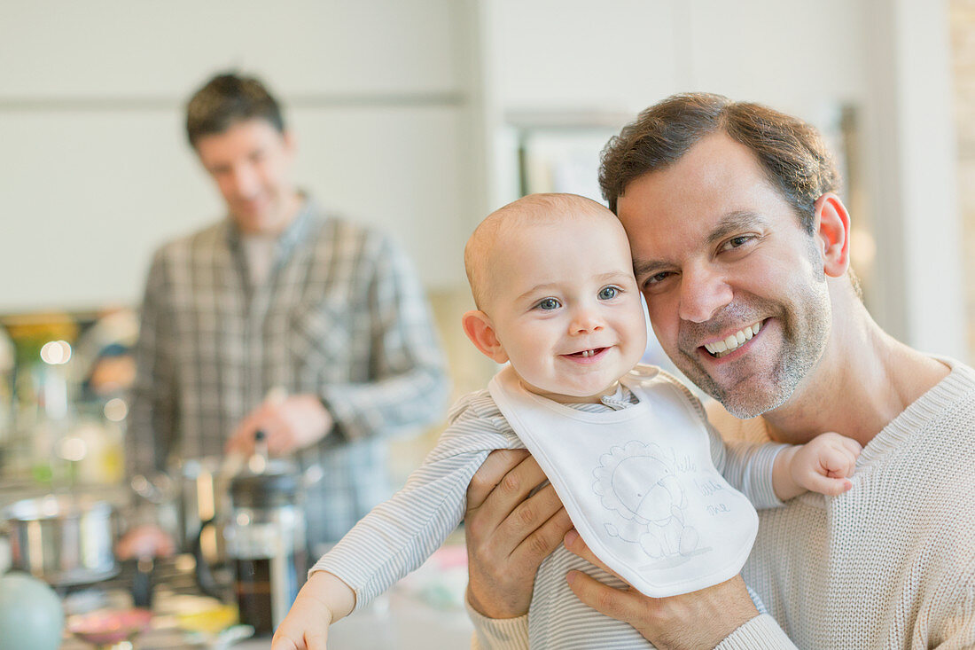 Portrait smiling gay father holding baby son
