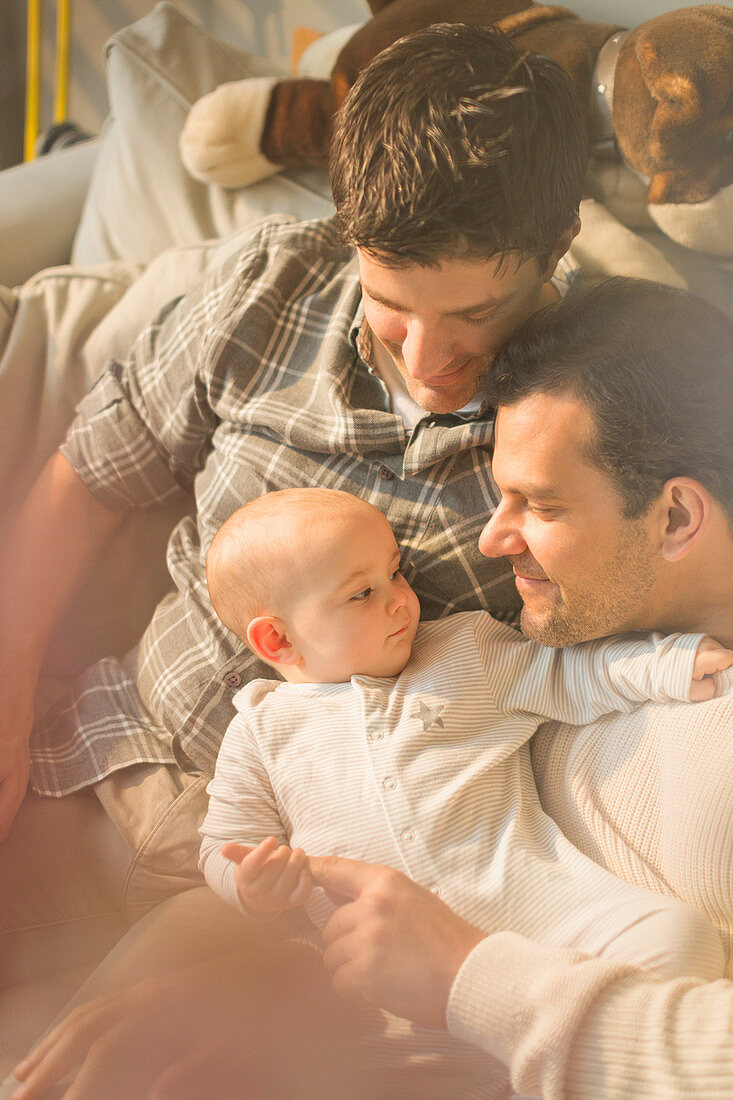 Affectionate male gay parents and son cuddling