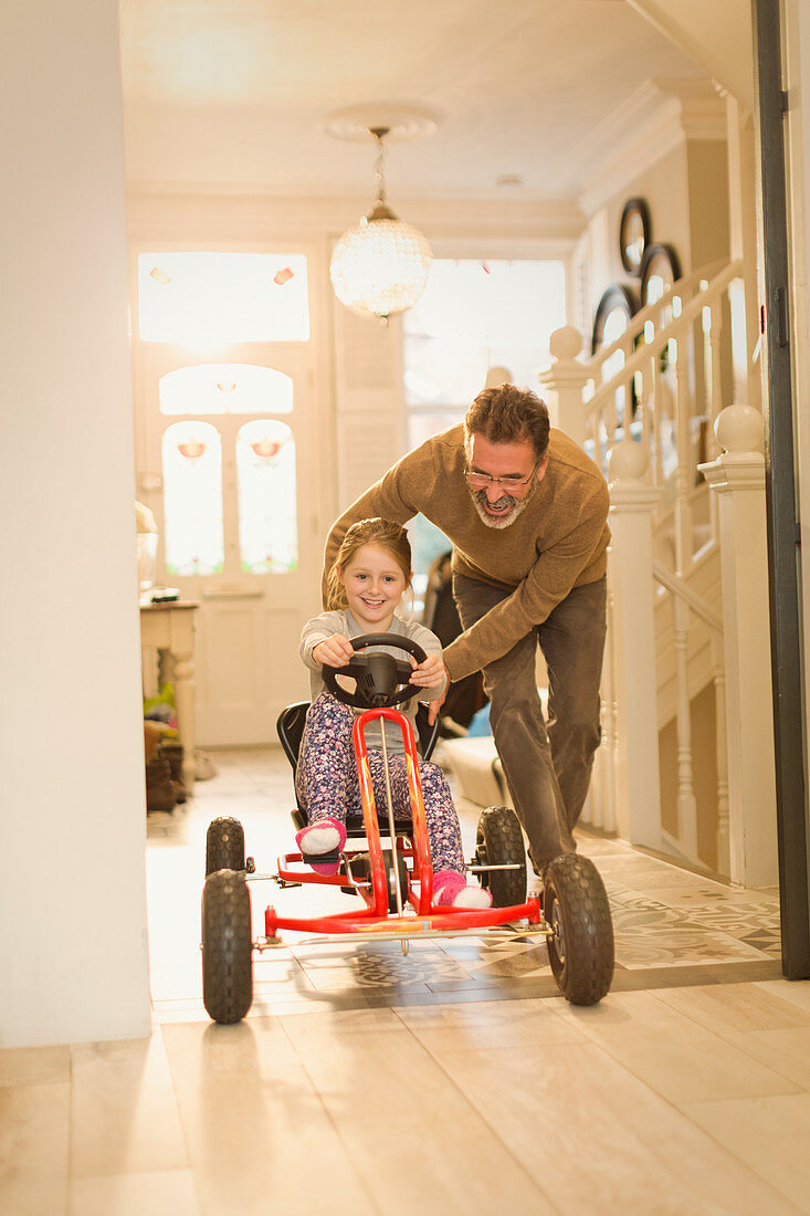 Father pushing daughter on toy car