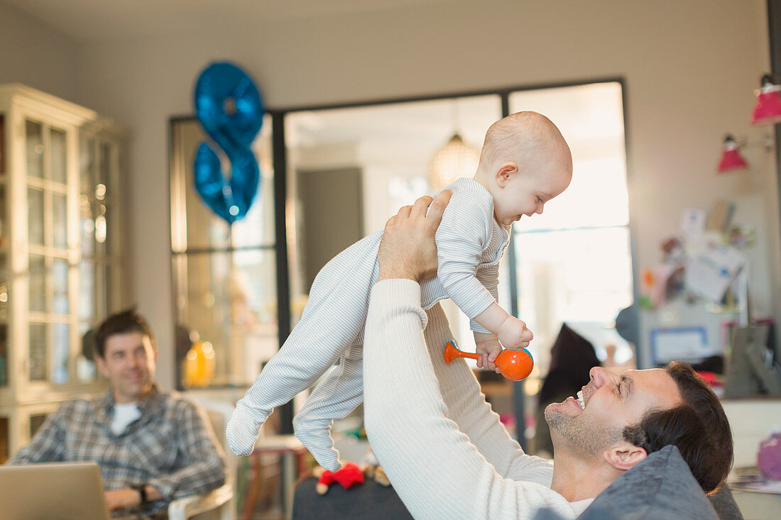 Male gay parents playing with baby son