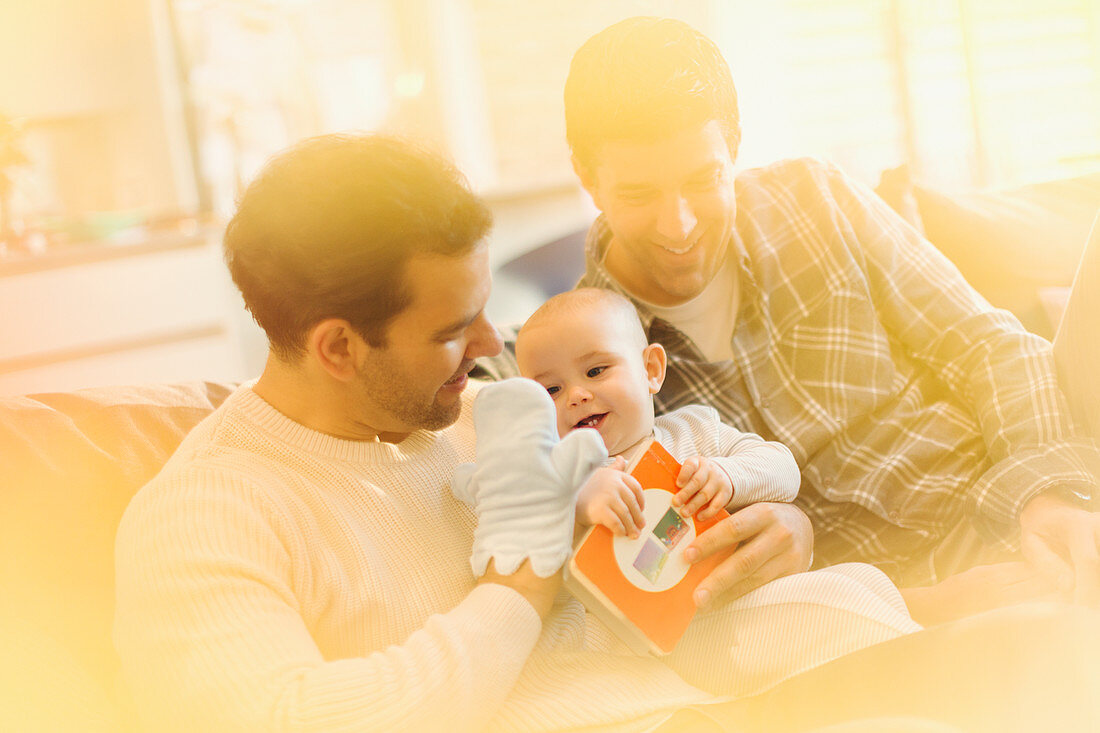 Male gay parents with puppet playing with baby son