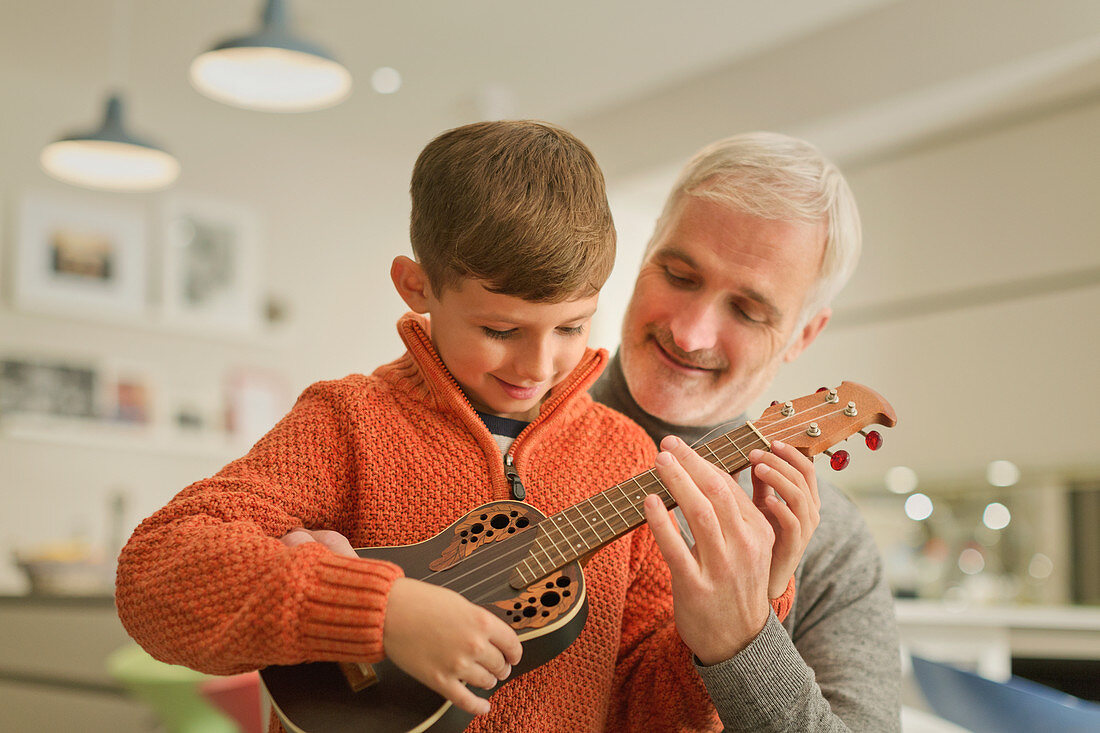 Father teaching son to play the ukulele