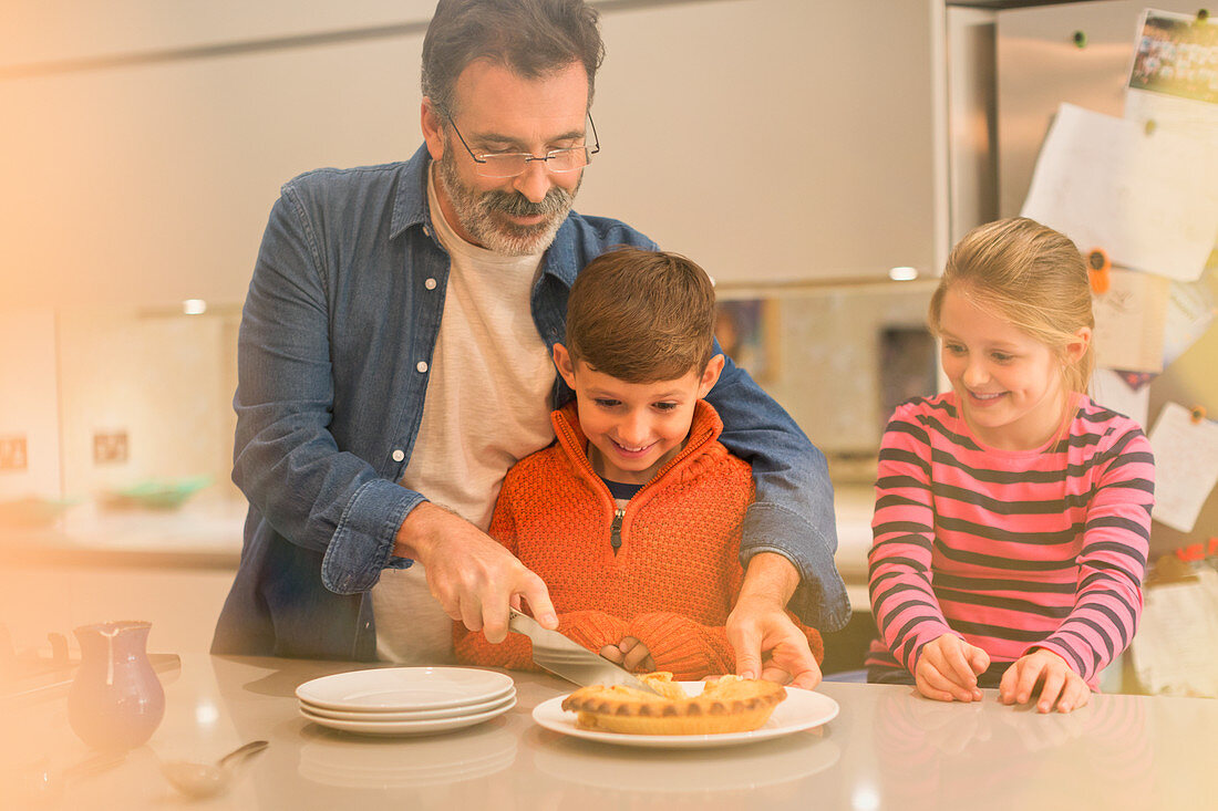 Father cutting and serving pie to children