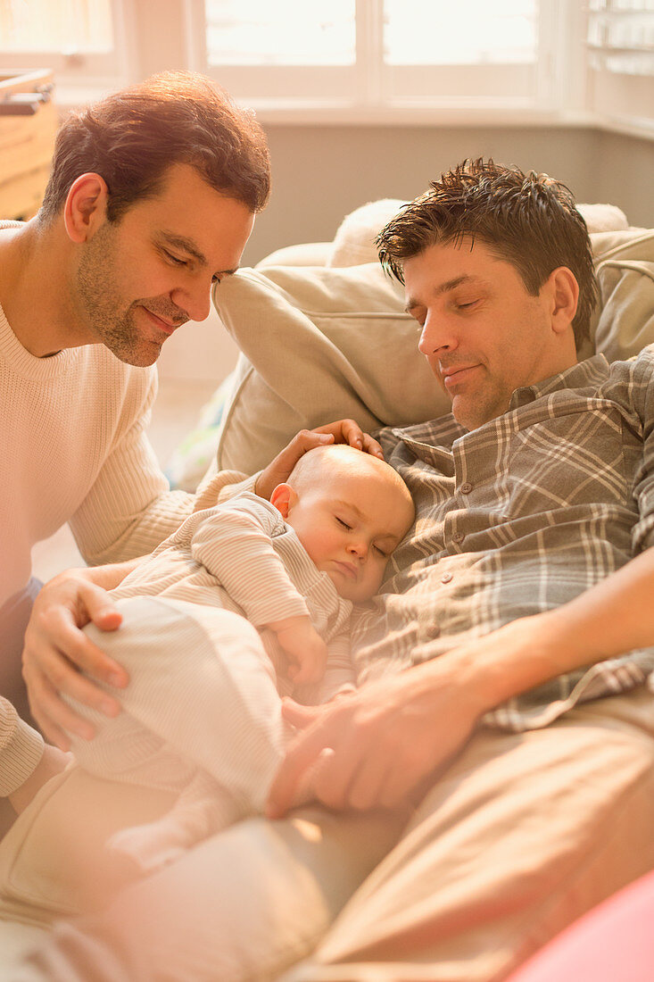 Male gay parents watching baby son sleeping