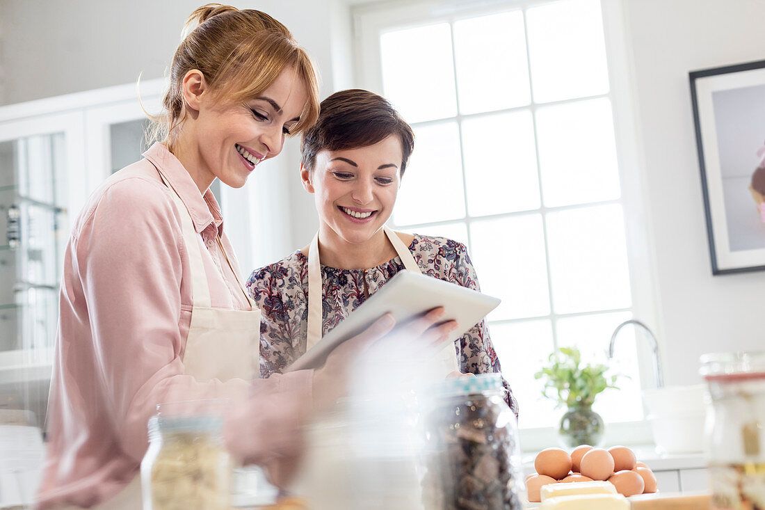 Smiling female caterers using tablet, baking