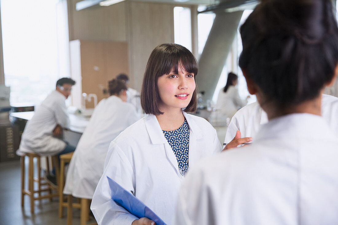 Female college students in lab coats talking