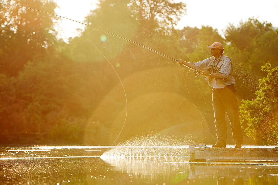 Senior man fly fishing at summer lake