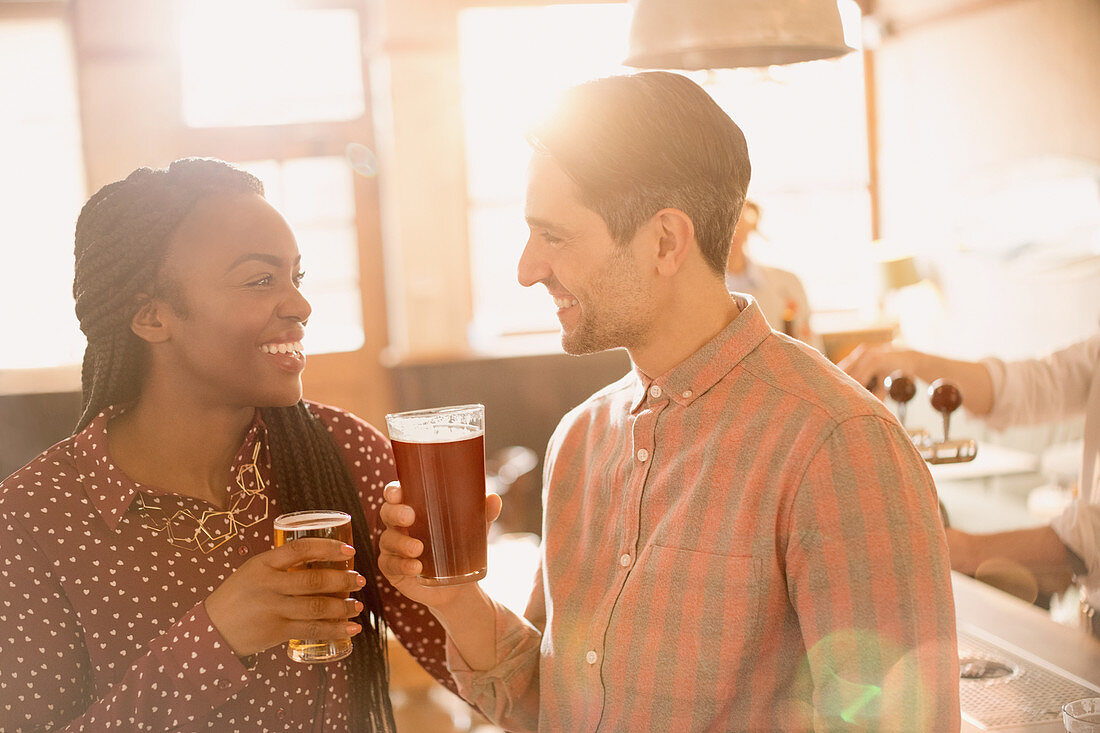 Smiling couple drinking beer in bar