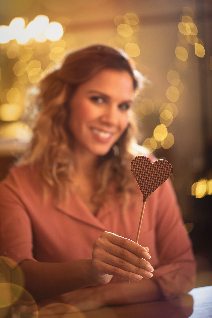 Portrait woman holding heart-shape lollipop