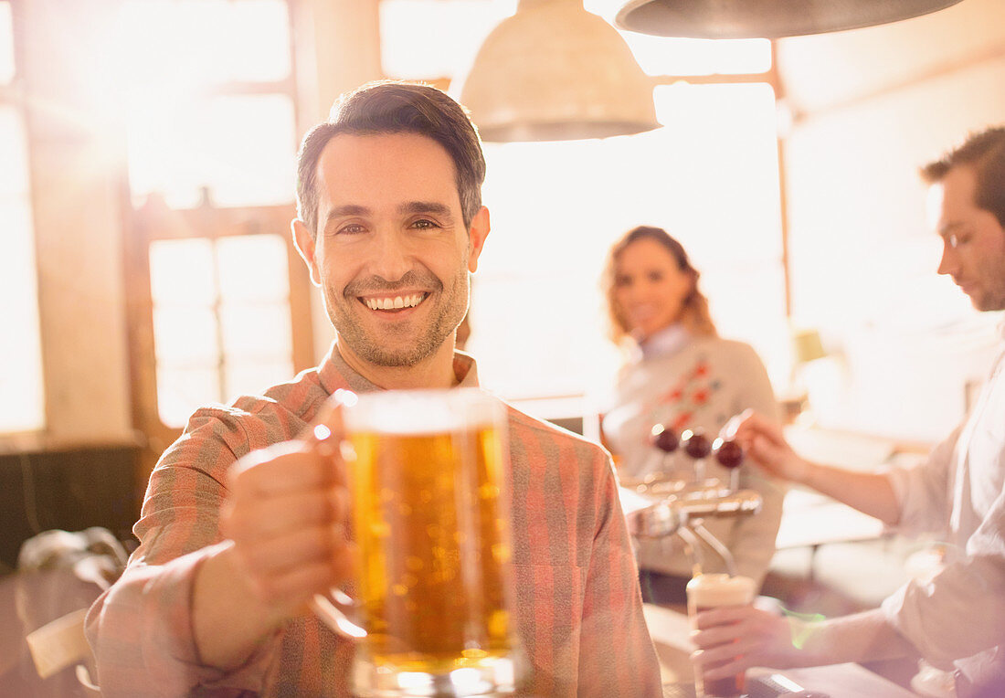 Portrait man toasting beer stein in bar